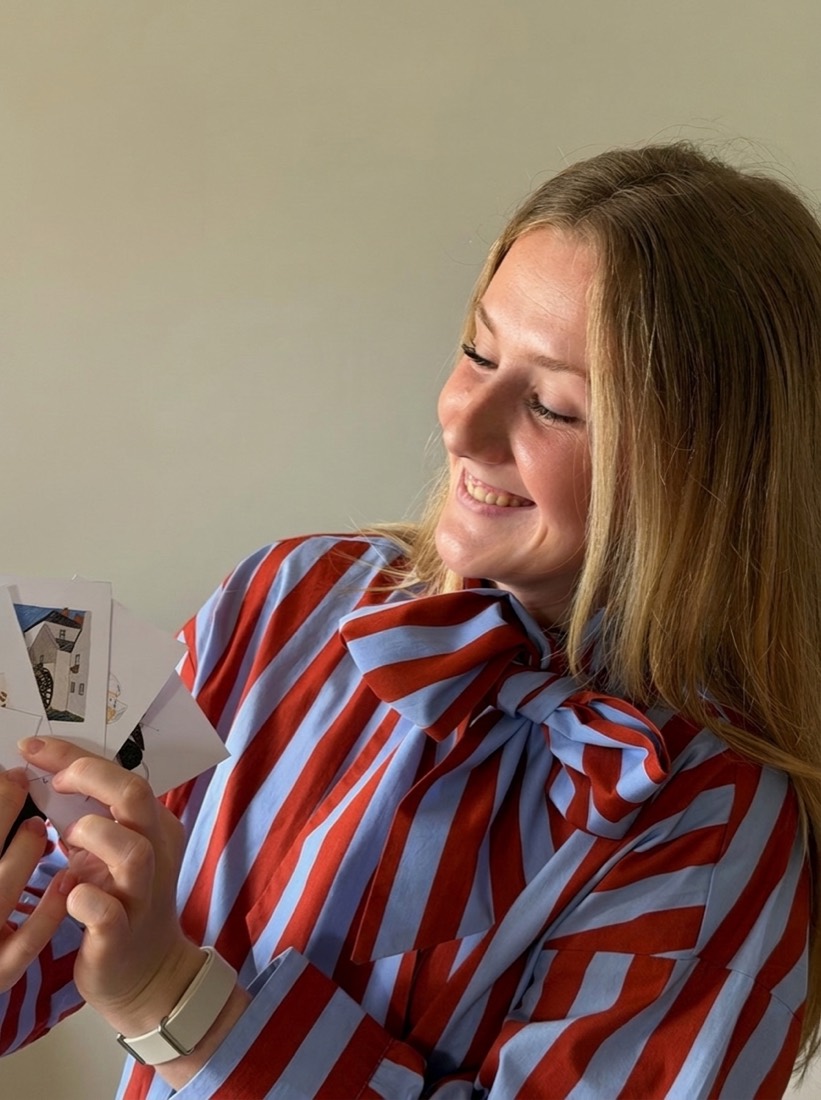 Portrait d'Inès, souriante, qui montre des cartes illustrées